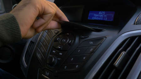 Mans hand puts the disk into the car player. Button control for compact disk player in a car. Hand...