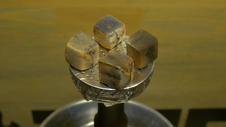 Mans hand puts burning coals on clay bowl with tobacco for hookah, Hookahs head. Hookah topic:...