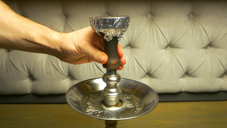 Smoke hookah on a black background with a beautiful smoke. Brown hookah bowl for tobacco with long...
