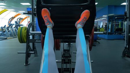 Close up shoes of a fit young woman doing leg press in the gym. Closeup of a fit young woman doing...