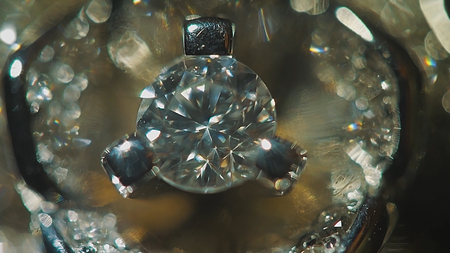 Diamond solitaire ring closeup in dark environment. Big blue diamond, closeup view. layered triangular macro diamond shapes with a small diamond over them. Round gemstone on Black Background with Reflectionの写真素材