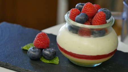 Homemade yogurt with blueberries in a glass jar. beautifully arranged berries to decorate the dessert, close up.の写真素材