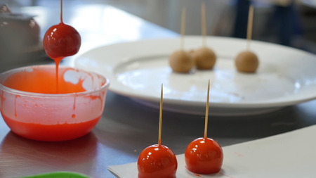 Woman dipping candy apple into bowl with caramelの写真素材