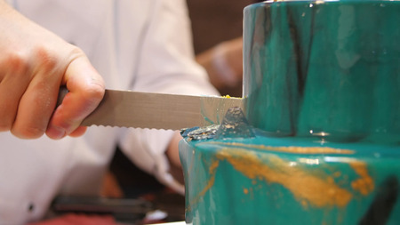 The pastry chef cut the cake with a long knife. Cut a turquoise cake. The pastry chef cut the cake.