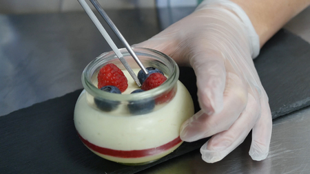 Homemade yogurt with blueberries in a glass jar. Hand putting Strawberry in Yogurt, close up.の写真素材