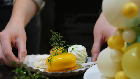 The female lays a piece of cake on a plate. Woman puts on a plate cake.の写真素材