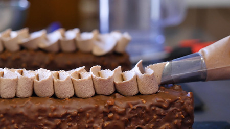 Baking a cake. Squeezing the cream on the cake. Delicious yummy cream squeezed on the cake.の写真素材