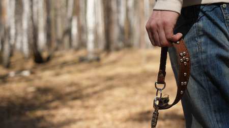 Man stands with a leash. Man waiting for the dog with the leash