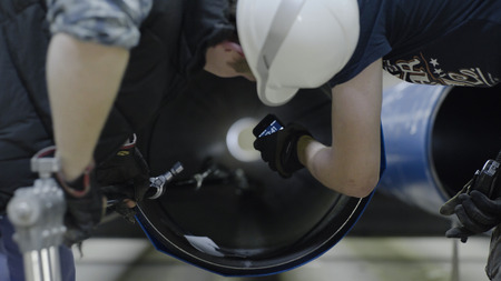 Working on tubular production. Men look inside the pipeの写真素材