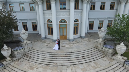 Aerial survey of the bride and groom who dance at the palace in the garden. Big white palace or castle view. Flying over the palace in the large yard.View of St. Petersburg.The couple walk near the Palace in a wedding dress and suit. Museum.St. Petersburgの写真素材