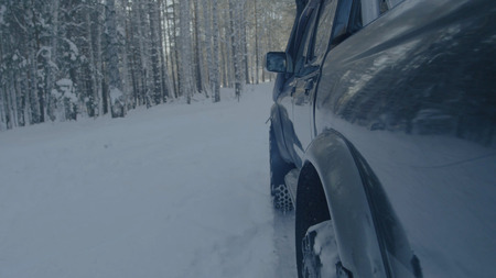 Car rides on a winter forest road. A car in a snow-covered road among treesの写真素材