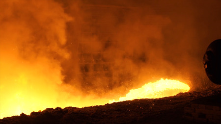 Liquid metal from blast furnace. Liquid metal pouring stream.