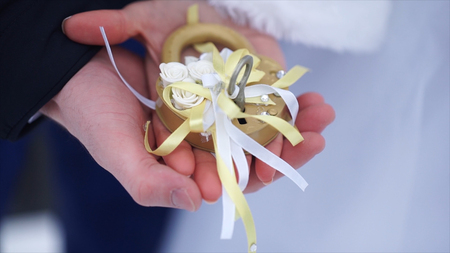 Wedding symbol, lock in hands of bride and groom. Newlyweds fix the lock on the bridge as a symbol...