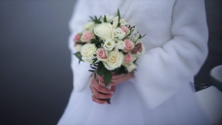 bride with flowers in hand outdoors. The bride is nervous before the wedding. Bride holding a perfume. nice wedding bouquet in brides hand. Bride is holding beautiful bright wedding bouquet. the bride holding wedding bouquet of pink and white roses. Womanの写真素材