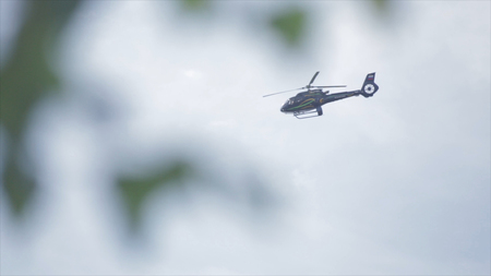 Helicopter flying in the sky behind or through tree branches view. Flying helicopters in the sky....