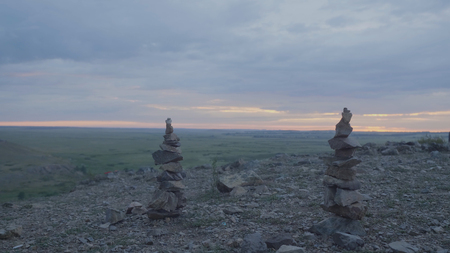Pebbles tower Zen and balance. Stack of the pebbles against the sky. Tower of stones on the background of the field and the morning sky.の写真素材