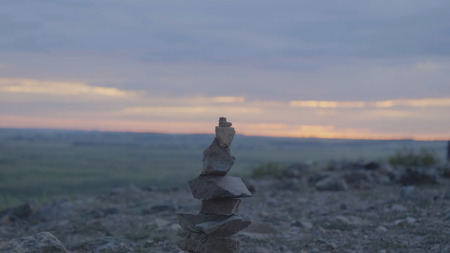 Pebbles tower Zen and balance. Stack of the pebbles against the sky. Tower of stones on the background of the field and the morning sky.の写真素材