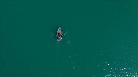 Aerial Boat on the lake. Aerial view on two men in a boat on a lake, rowed to the shore. Lonely boat in the middle of the river, lake. Boat single row on sea with reflection in the water in the morning light. Singleの写真素材