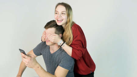 beautiful happy smiling woman covering eyes with her hands of handsome young man in fun moodの写真素材