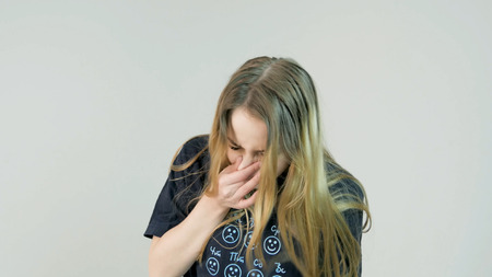 Blond woman sneezing on white backgroundの写真素材