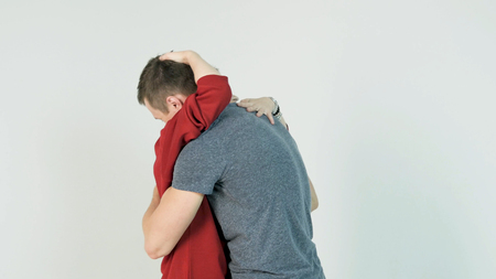 Young man hugging girlfriend. Young couple embraces after a long separation, on a white backgroundの写真素材