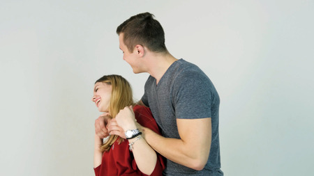 Young man hugging girlfriend. Young couple embraces after a long separation, on a white background