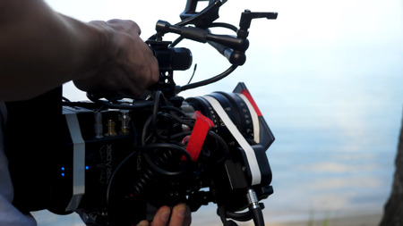 Man holding a camera filming a movie in the forest. Expensive camera for movie in the woodsの写真素材