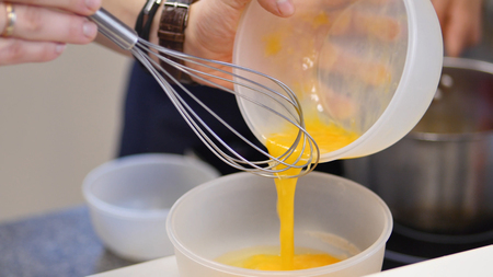 whipped egg yolks with sugar in a glass bowl. Beaten egg yolks in a bowl with whisk. Beaten egg yolkの写真素材
