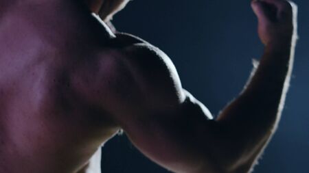Fighter silhouette. Handsome athletic man in boxing stand on a dark background. Muscular young man in boxing gloves and shorts shows the different movements and strikesの写真素材