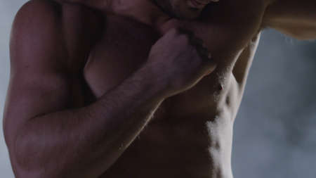 Punches close up in smoke dark background. Muscular kickbox or muay thai fighter punching in smokeの写真素材