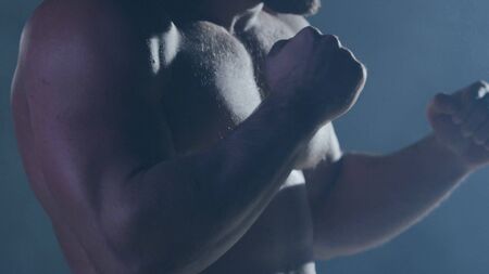 Boxing man ready to fight. Boxer with strong hands and clenched fists on a black background....