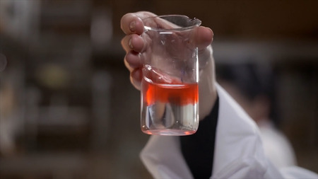 Young scientist works in modern biological lab. A researcher in a lab coat studying a piece of...