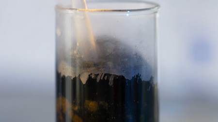 Black mixture out of the flask. glass flasks on black backgroundの写真素材