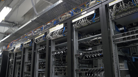 Row of bitcoin miners set up on the wired shelfs. Computer for Bitcoin mining. cables plug to...