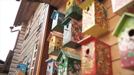 Colorful bird houses. Handmade wooden birdhouse on log house. Birdhouses on the wall. Neighborhood. Wooden birdhouse in vintage styleの写真素材