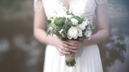 Beautiful bouquet of different colors in the hands of the bride in a white dress. Bride in white dress with bouquet. Woman holds wedding bouquet. Weddingの写真素材