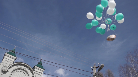 Blue birthday party balloons flying. A planty of blue balloons in the sky. Pink and yellow air balloons fly high in the sky. Sunny day with white fluffy clouds HDの写真素材
