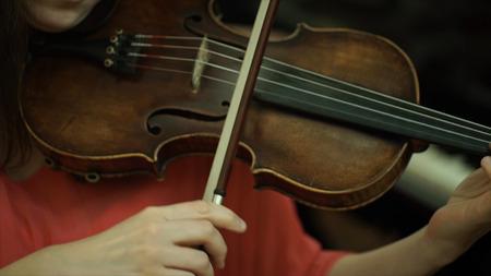 Girls hand on the strings of a violin. Girls hand on the fingerboard violin.の写真素材