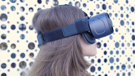 Woman using a virtual reality headset on white futuristic background. Young attractive woman using...