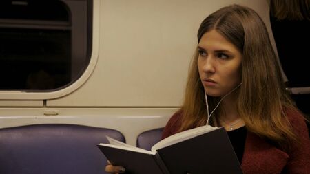 Beautiful girl reading a book in train at the subway. Teenager girl read a book in train or subway carの写真素材
