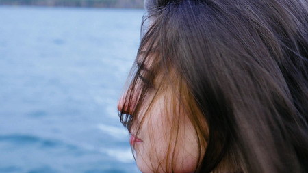Close up of young Woman Relaxing near Lake. Romantic beautiful woman enjoying her time and peaceful nature. Calm and cozy eveningの写真素材