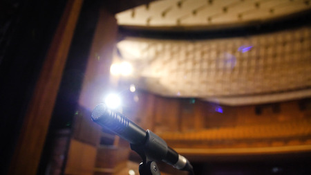 Microphone on the stage and empty hall during the rehearsal. Microphone on stage with stage-lights in the background. Microphone on the stage in the empty hall.の写真素材