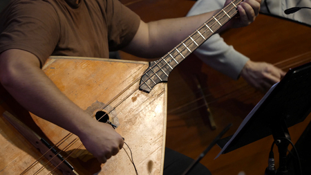 Balalaika wooden in the hands of the musician. Folk musical art of the rural traditional. Man plays the Balalaika-contrabassの写真素材