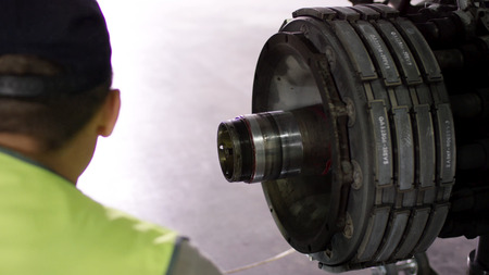 Airport worker checking chassis. Engine and chassis of the passenger airplane under heavy...
