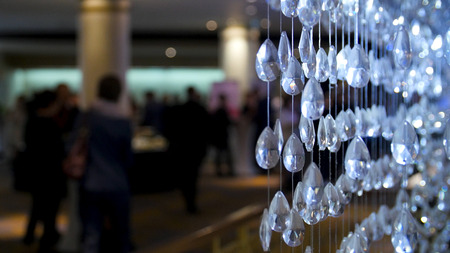 Glass chandelier crystals close up and people background, selective focus.の写真素材