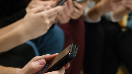 Closeup of friends chatting on mobile phone in network. Group of friends are using gadgets during...