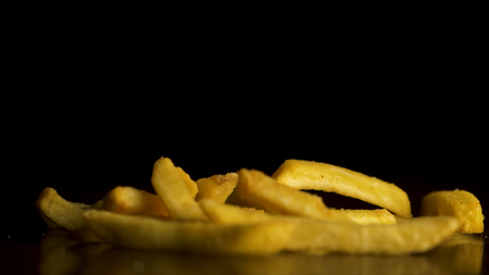 Fries falling isolated on black background. French fries fall on the table isolated on black background. Flying chips closeup.の写真素材