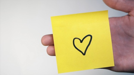Man's hand put blank yellow sticker isolated on a white background. I Love You Hの写真素材