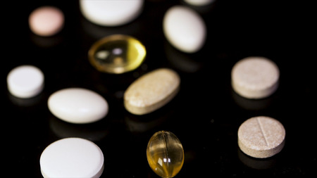 Various colorful pills on black background. Pile of several medicines on black background. Colorful pills over dark background. white pills on black glass background. medical pharmacyの写真素材