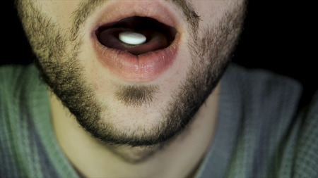 Bearded man swallows a pill. Close up of man showing tablet on the tongue and swallows it, the...